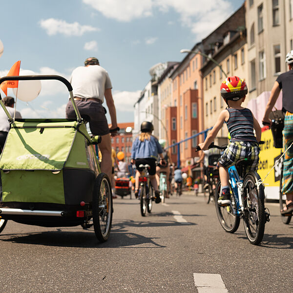 Familie bei Sternfahrt in Berlin Familie auf Rändern mit Fahrradanhänger auf städtischer Straße von hinten zu sehen